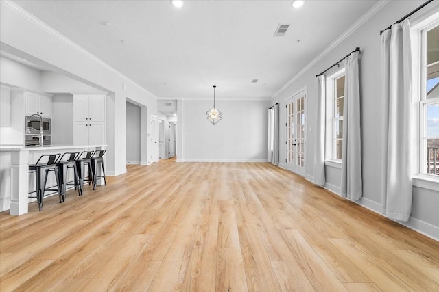 living area with ornamental molding, light wood-type flooring, visible vents, and baseboards