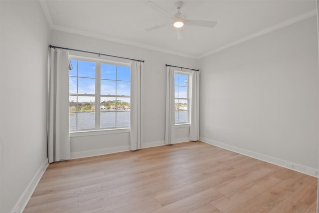 unfurnished room featuring light wood-style floors, a water view, crown molding, and baseboards