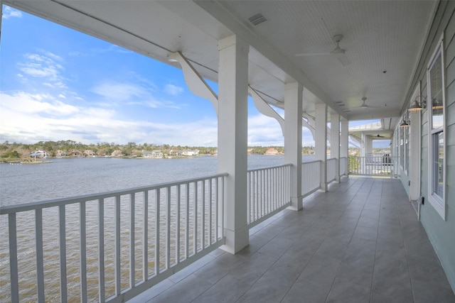 balcony with a ceiling fan, a water view, and visible vents