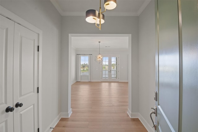 hallway featuring baseboards, french doors, light wood-type flooring, and crown molding