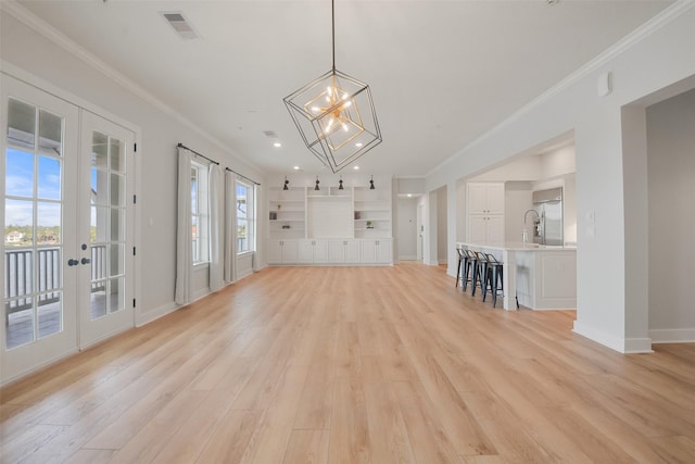 unfurnished living room with ornamental molding, light wood finished floors, visible vents, and baseboards