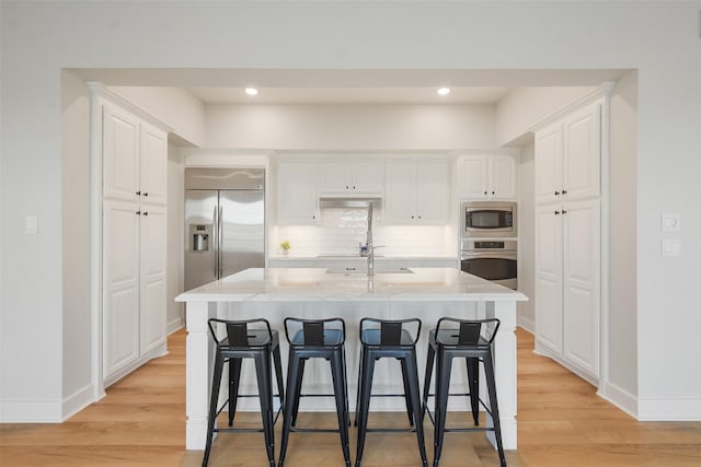 kitchen featuring a kitchen island with sink, white cabinets, and built in appliances