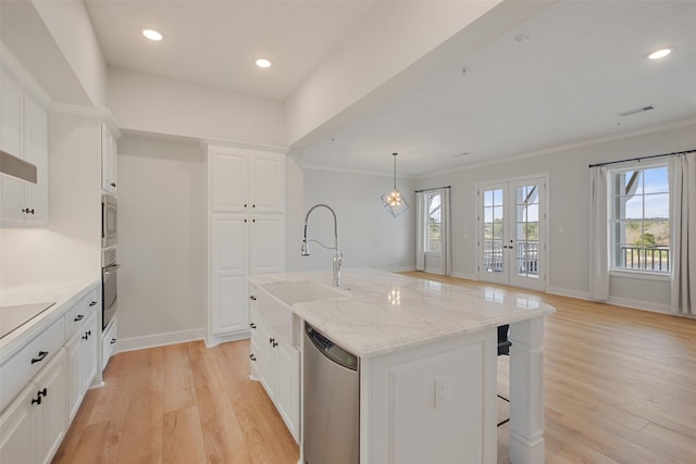 kitchen with light stone counters, white cabinetry, appliances with stainless steel finishes, a center island with sink, and pendant lighting