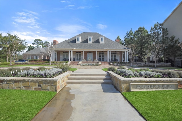 view of front of property with a porch, a front yard, and a shingled roof