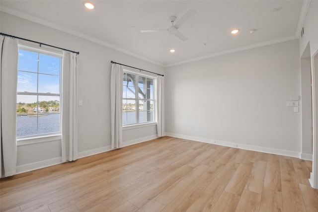 empty room with ornamental molding, light wood-style flooring, and baseboards