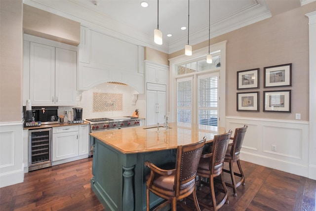 kitchen with premium appliances, wine cooler, white cabinetry, and hanging light fixtures