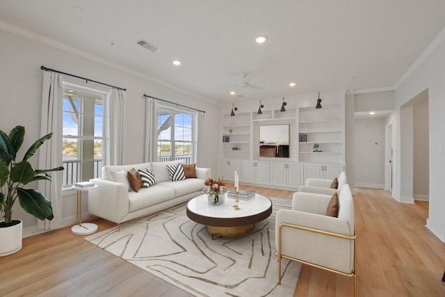 living area with ornamental molding, light wood-style flooring, and visible vents