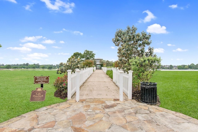 view of property's community featuring a lawn and fence