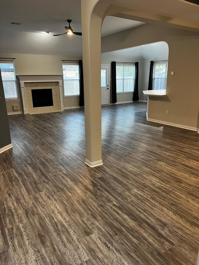 unfurnished living room with ceiling fan, plenty of natural light, dark hardwood / wood-style flooring, and a tile fireplace