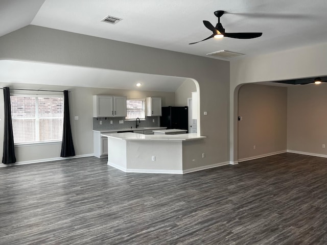 kitchen featuring lofted ceiling, dark wood-type flooring, black refrigerator, white cabinetry, and decorative backsplash