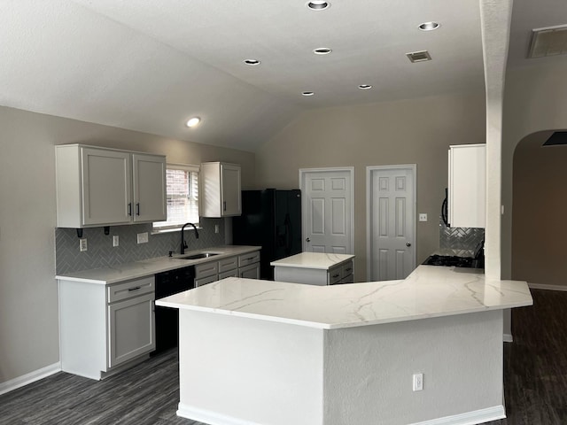 kitchen featuring sink, black appliances, light stone countertops, a kitchen island, and kitchen peninsula