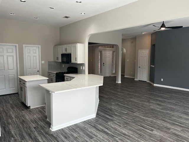 kitchen featuring dark wood-type flooring, kitchen peninsula, a kitchen island, decorative backsplash, and black appliances