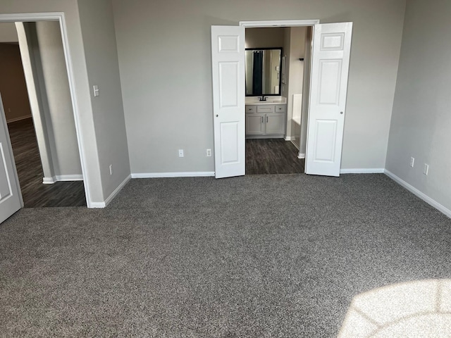 unfurnished bedroom featuring dark colored carpet and connected bathroom