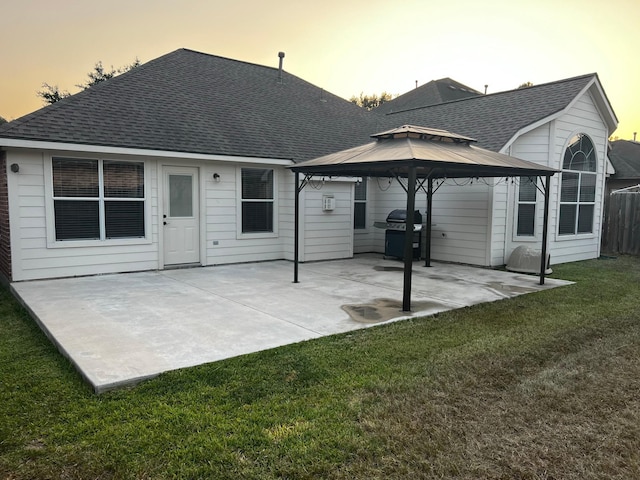 back house at dusk featuring a gazebo, a lawn, and a patio area