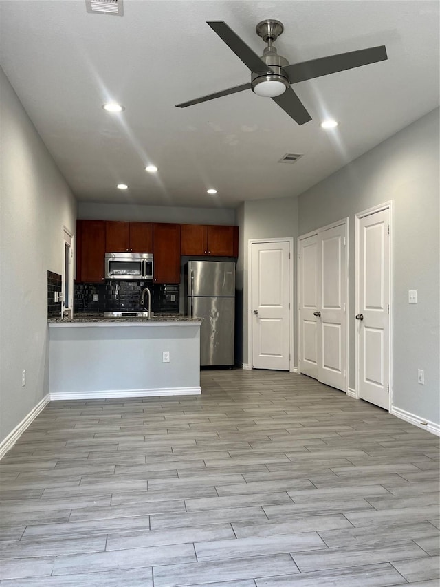 kitchen featuring sink, appliances with stainless steel finishes, tasteful backsplash, light hardwood / wood-style floors, and kitchen peninsula