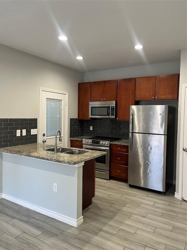 kitchen featuring appliances with stainless steel finishes, kitchen peninsula, sink, and light stone countertops