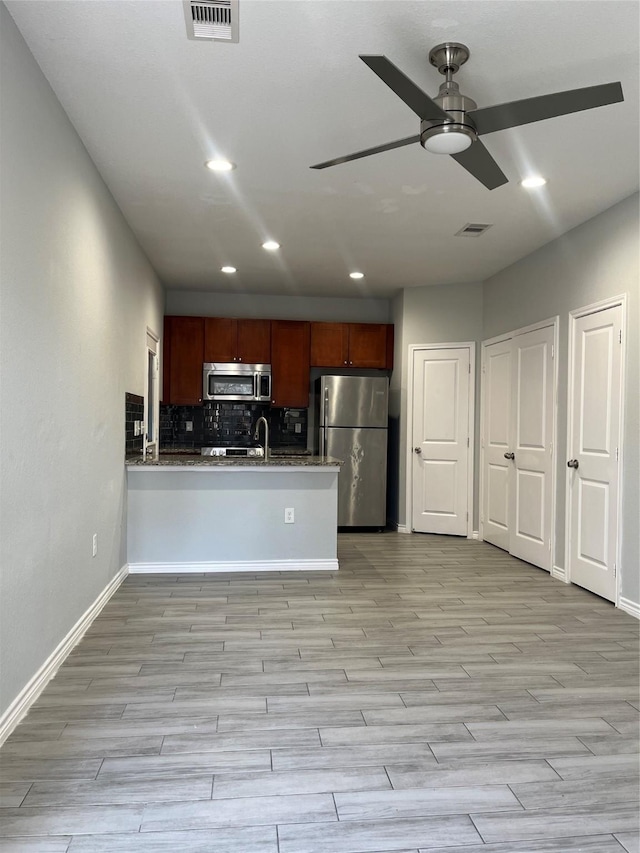 kitchen with sink, light hardwood / wood-style flooring, backsplash, stainless steel appliances, and kitchen peninsula