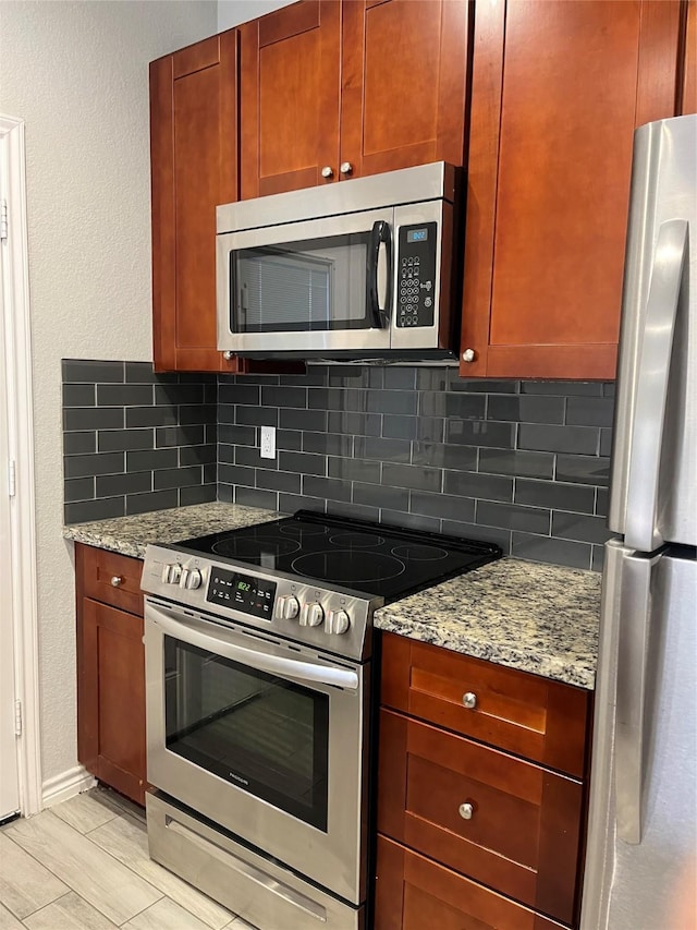 kitchen with tasteful backsplash, appliances with stainless steel finishes, and light stone counters