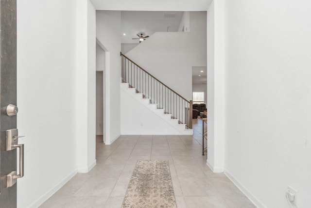 entryway with a towering ceiling, light tile patterned floors, and ceiling fan