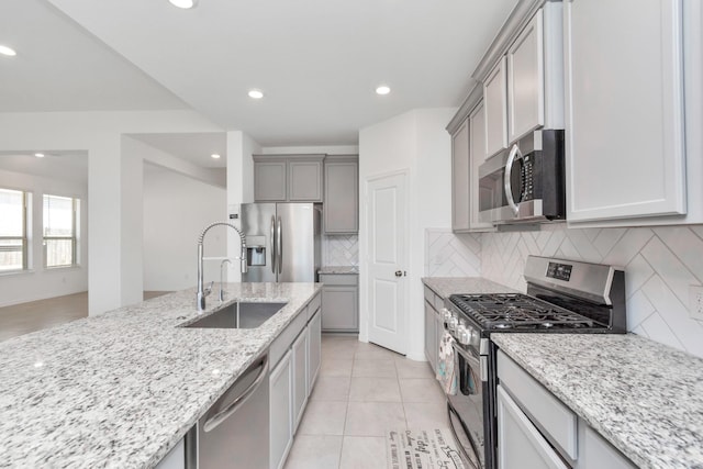 kitchen featuring sink, decorative backsplash, light tile patterned floors, light stone counters, and stainless steel appliances