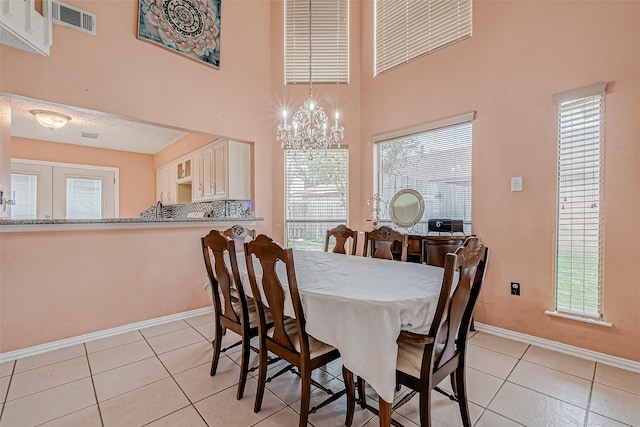 dining room with an inviting chandelier, light tile patterned floors, and a towering ceiling