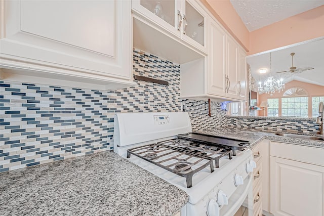 kitchen featuring tasteful backsplash, white cabinetry, lofted ceiling, sink, and white range with gas stovetop