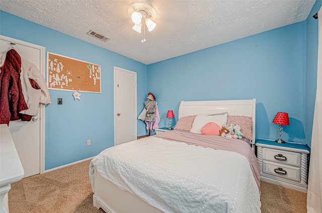 carpeted bedroom featuring ceiling fan and a textured ceiling