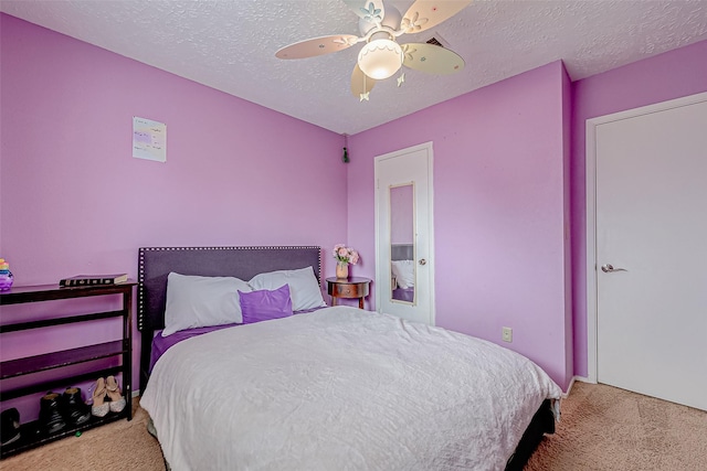 bedroom with ceiling fan, light colored carpet, and a textured ceiling