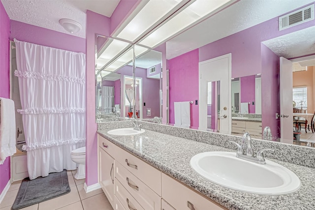 bathroom with tile patterned flooring, vanity, a textured ceiling, and toilet