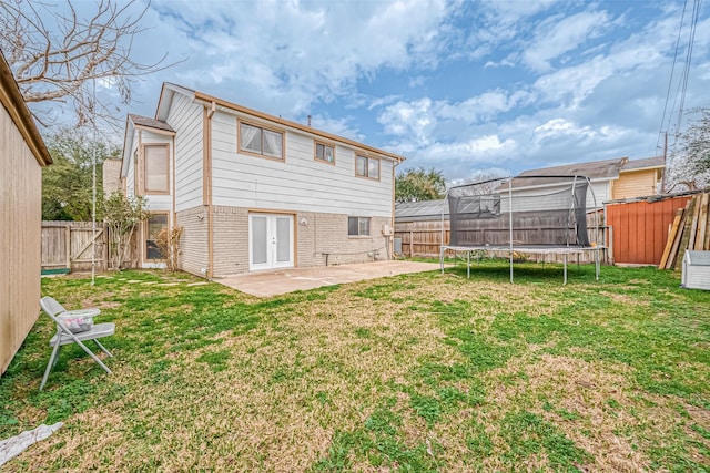 rear view of house with a lawn, a trampoline, and a patio area