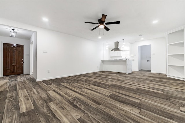 unfurnished living room featuring dark wood-type flooring and ceiling fan