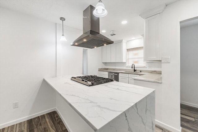 kitchen featuring sink, island range hood, hanging light fixtures, kitchen peninsula, and white cabinets