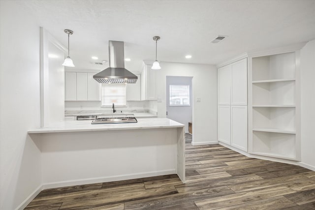 kitchen with dark wood-type flooring, white cabinetry, hanging light fixtures, kitchen peninsula, and island exhaust hood