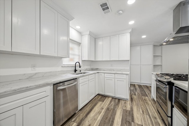 kitchen with sink, white cabinets, stainless steel appliances, hardwood / wood-style floors, and wall chimney range hood