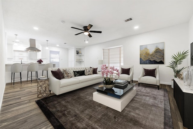 living room featuring dark wood-type flooring and ceiling fan