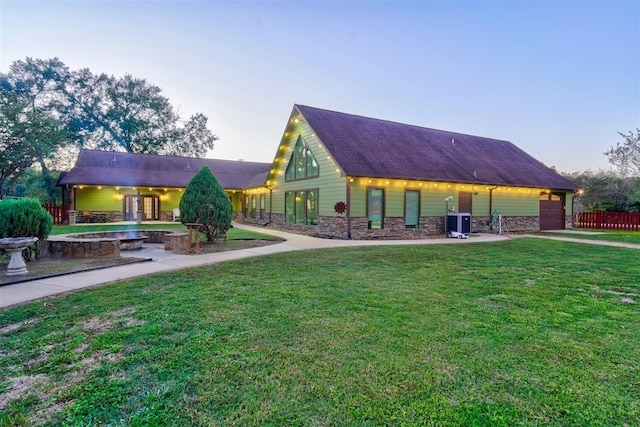 exterior space featuring a front lawn, stone siding, and a garage