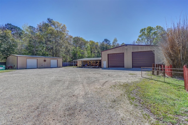 detached garage featuring driveway and fence
