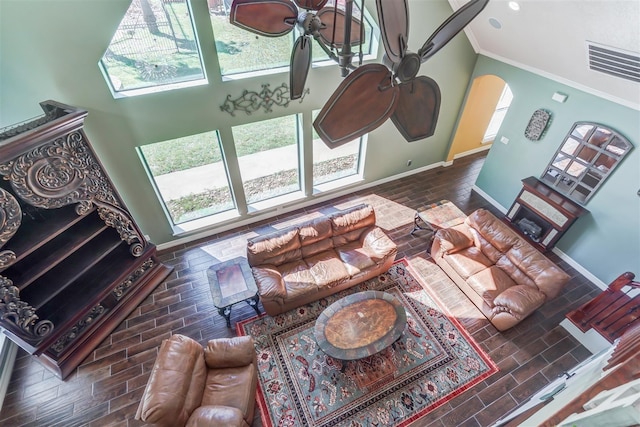 living room with crown molding, baseboards, and arched walkways