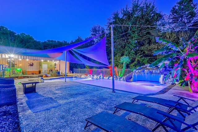 pool at twilight with a patio, a fenced in pool, and fence