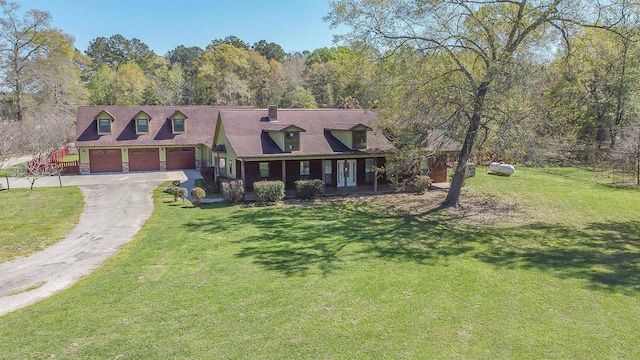 new england style home featuring an attached garage, a front lawn, and driveway