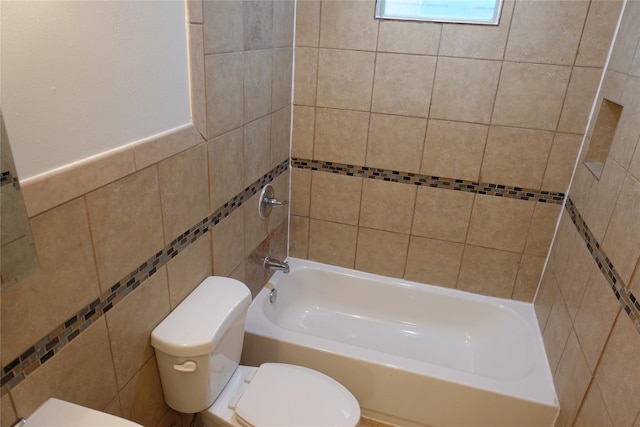 bathroom featuring tiled shower / bath, tile walls, and toilet