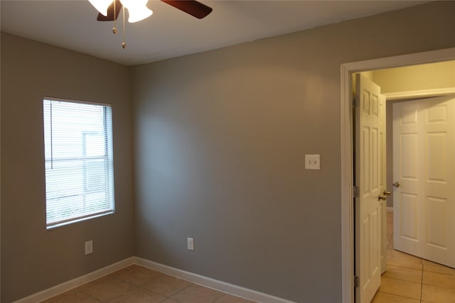 tiled spare room featuring ceiling fan