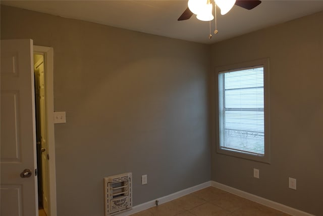 spare room with ceiling fan, heating unit, and light tile patterned floors