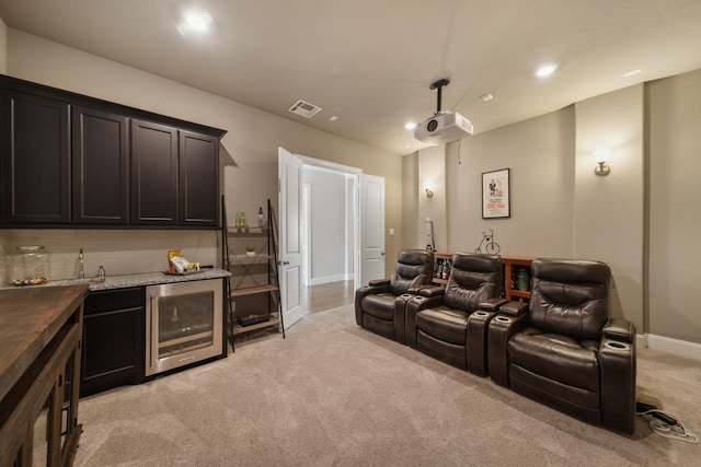 cinema room with wine cooler, indoor bar, and light carpet