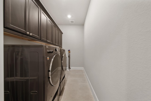 washroom with cabinets and washing machine and dryer