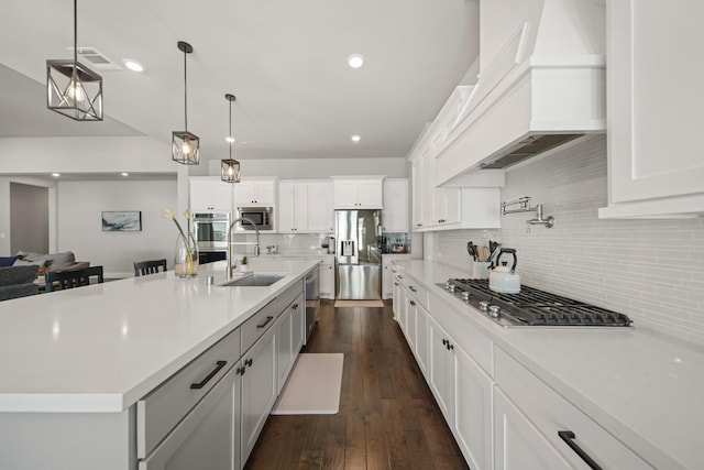 kitchen featuring white cabinetry, sink, a large island with sink, hanging light fixtures, and stainless steel appliances