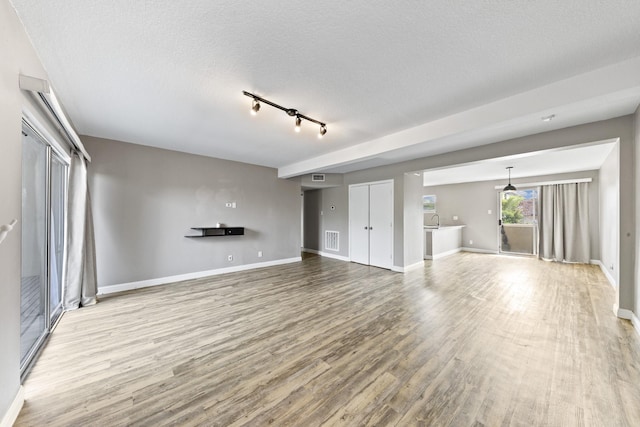 unfurnished living room featuring light hardwood / wood-style floors and a textured ceiling