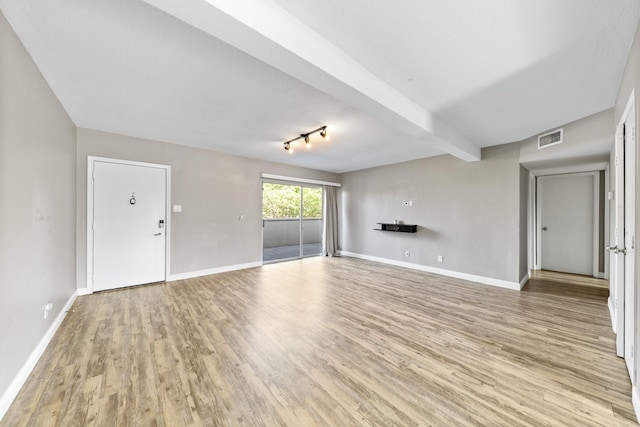 unfurnished living room featuring beam ceiling and light hardwood / wood-style floors