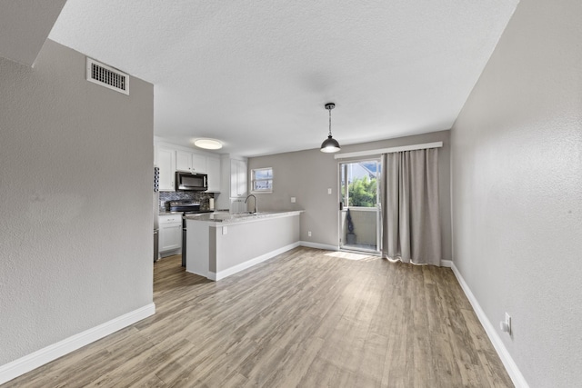 kitchen with decorative light fixtures, backsplash, white cabinets, electric range, and light hardwood / wood-style floors