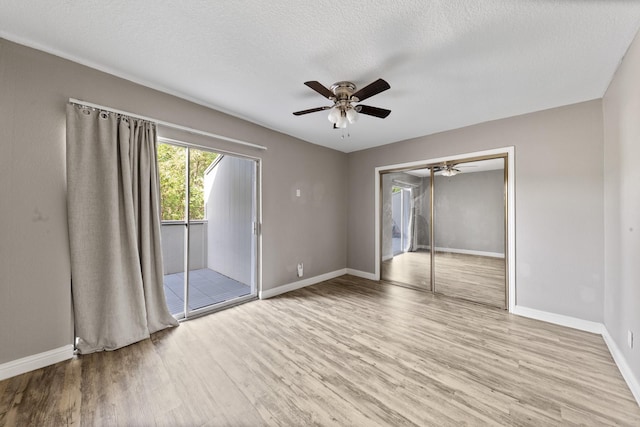 unfurnished room with ceiling fan, a textured ceiling, and light wood-type flooring